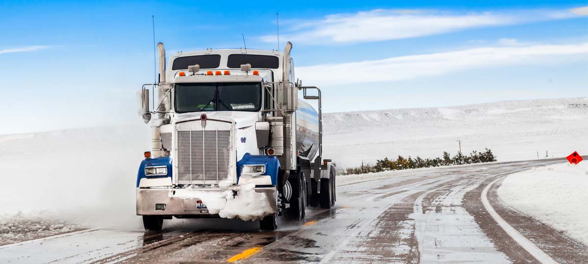 Semi truck driving on a snowy highway during winter conditions